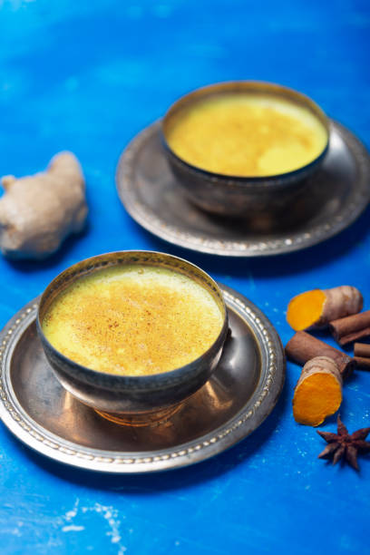 istock Golden turmeric milk on the blue background with ingredients 1166498351