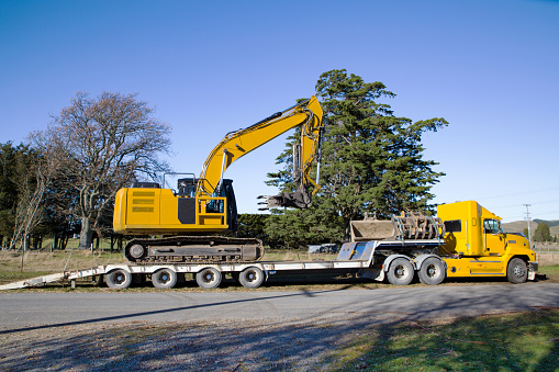 Heavy machinery is transported to and from a rural job site by a truck and trailer in Canterbury, New Zealand