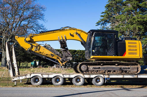 Heavy machinery is transported to and from a rural job site by a truck and trailer in Canterbury, New Zealand