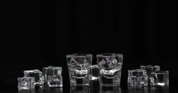 istock Shots of vodka with ice cubes against black background 1166503607
