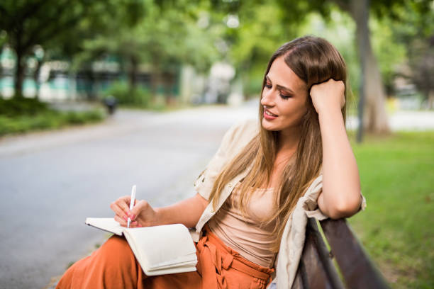 istock Young woman taking notes outdoors i in the park. 1166506015