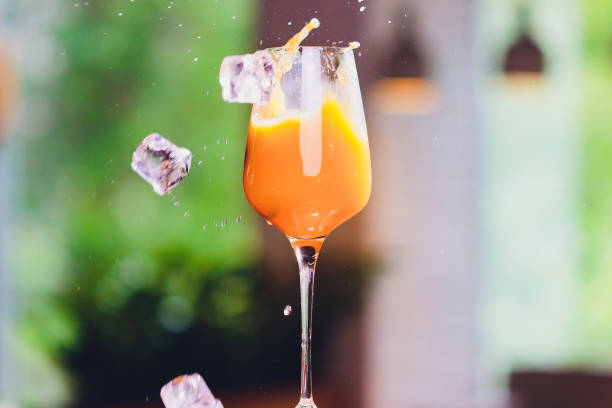 istock ice cubes falling into a splashing orange cocktail. 1166511500