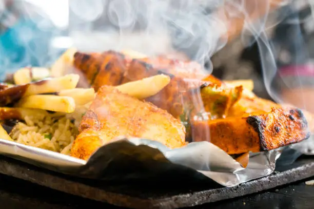 Delicious paneer, french fries and vegetble sizzler giving off smoke and steam. This dish is a favorite in north india and comes in vegetarian and non vegetarian variants and various ingridients