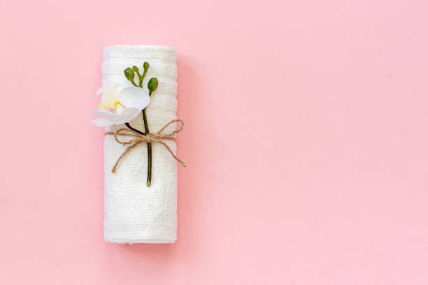 White towel roll tied with rope with sprig of orchid flower on pink paper background. Copy space Template for lettering text or your design White towel roll tied with rope with sprig of orchid flower on pink paper background. Copy space Template for lettering text or your design. snow white and the seven dwarfs photos stock pictures, royalty-free photos & images