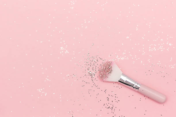 Makeup brush and shiny sparkles on pastel pink background. Festive magic makeup concept. Template for design, Top view Flat Lay Copy space stock photo