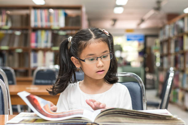 School education and literacy concept with Asian girl kid student learning and reading book in library or classroom School education and literacy concept with Asian girl kid student learning and reading book in library or classroom literacy photos stock pictures, royalty-free photos & images