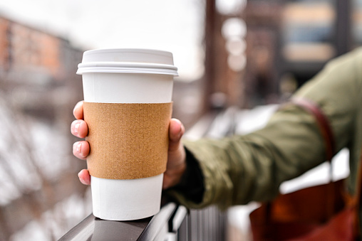 Holding a blank coffee cup with a out of focus city background. Photo taken in the winter in Minneapolis, Minnesota.