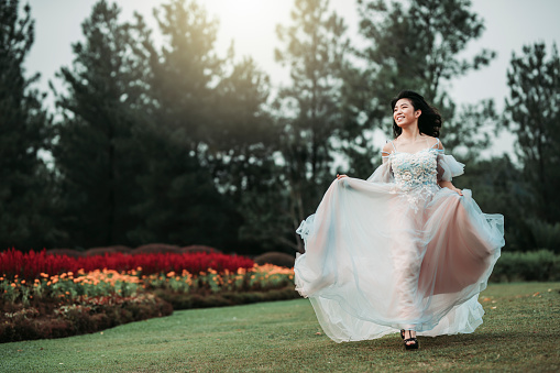 an asian chinese female model dress up with wedding gown for outdoor portrait session at public park in evening