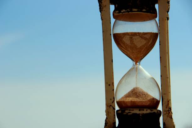 istock hourglass on the background of blue sky and white clouds 1166524680
