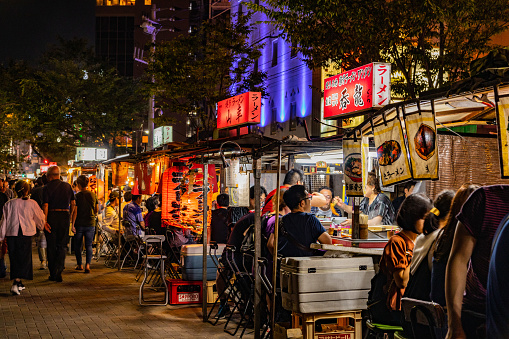 Many people in The Nakasu red-light district on the Nakasu Riverside on Saturday night FUKUOKA, JAPAN - July 6, 2019.  Nakasu is famous for Japanese style Yatai, Many people comes at night.