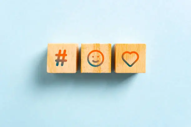 Photo of Hashtag, happy smiling face and heart icons on wood blocks toys and blue background. Rating and viral concept.