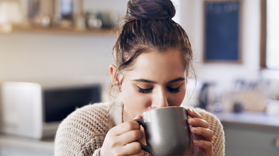 Shot of a beautiful young woman having a cup of coffee in the kitchen at home