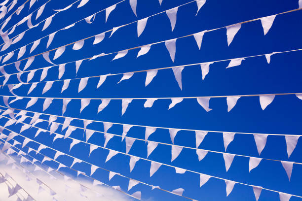 White flags waving on wind, navy blue sky background close up, banners flap on breeze, decorative garlands floats in air, beautiful billowing flags lines above, flying triangular flags design element