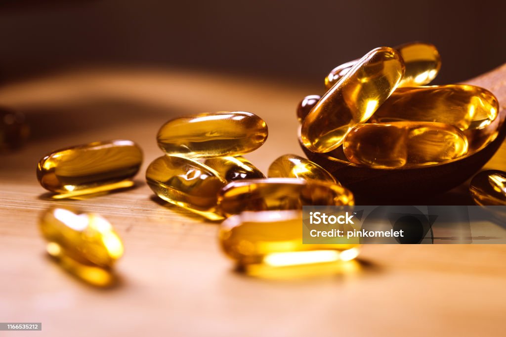 Close up the vitamin D and Omega 3 fish oil capsules supplement on wooden plate for good brain , heart and health eating benefit Close up vitamin D and Omega 3 fish oil capsules supplement on wooden plate for good brain , heart and health eating benefit Omega-3 Stock Photo