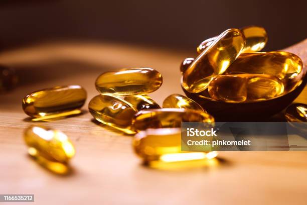Close Up The Vitamin D And Omega 3 Fish Oil Capsules Supplement On Wooden Plate For Good Brain Heart And Health Eating Benefit Stock Photo - Download Image Now