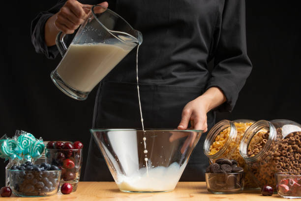 istock Pouring milk into the breakfast, freezing in motion. Cooking breakfast cereals, granules, breakfast cereals, cereals, berries of cherries, and blueberries, sweet cookies. On a black background 1166536200