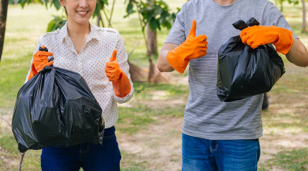 jeunes volontaires asiatiques de couples mâles et femelles avec des gants donnant des pouces vers le haut tout en recueillant des déchets dans le sac de poubelle dans le stationnement vert - hand sign human hand ok sign grass photos et images de collection