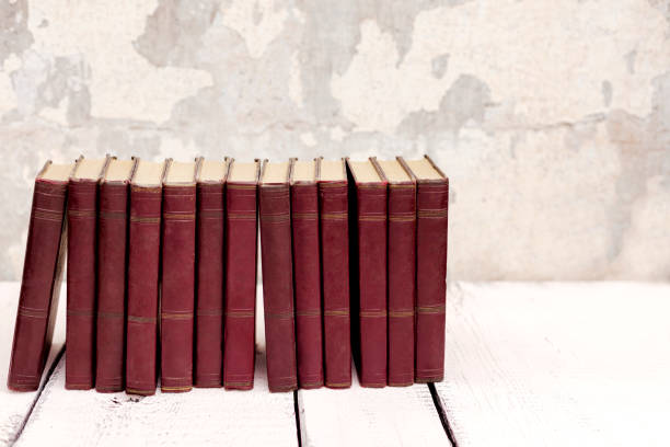 istock Stack of old ancient shabby books on a white wooden background. 1166545804