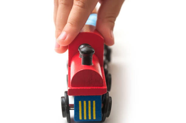 istock hand of kid playing with wooden train on white background 1166547656