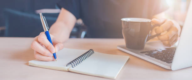 istock Woman hand is writing on a notepad with a pen in office.Web banner. 1166551240