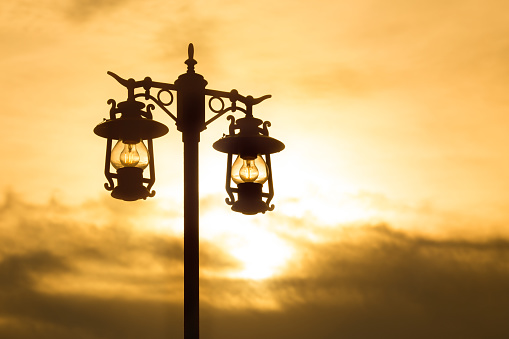 silhouette wrought iron street lamp at sunset