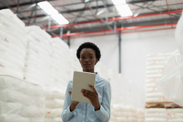 istock Female manager looking at camera while working on digital tablet in warehouse 1166555939