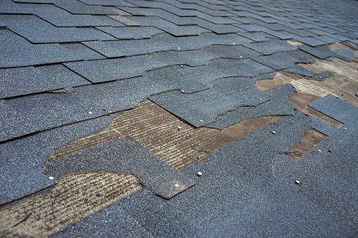 Vista de cerca de las tejas de betún daños en el techo que necesitan reparación. photo