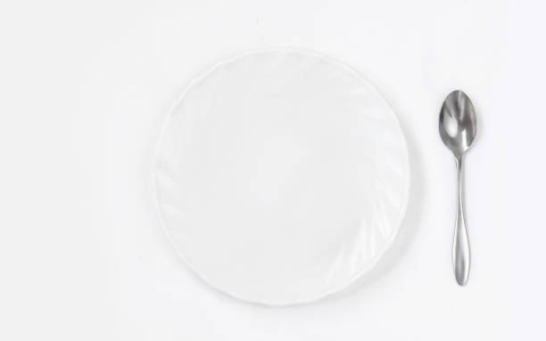 istock Round White plate with spoon on white background top view. Flat lay 1166557359