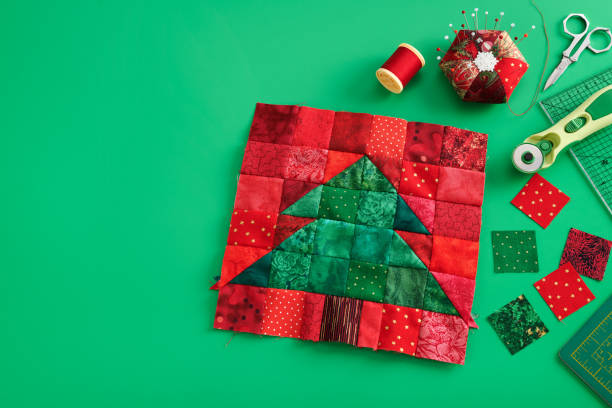 christmas tree patchwork block, bright square pieces of fabric, pincushion, quilting and sewing accessories on green background - christmas quilt craft patchwork imagens e fotografias de stock