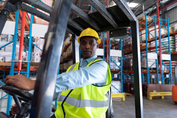 istock Male worker looking at camera while driving forklift in warehouse 1166558453