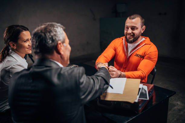 Three people, man and woman detectives investigating a man prisoner in dark investigation room,  shaking hand with lawyer.