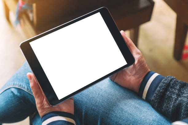 istock a woman sitting and holding black tablet pc with blank white desktop screen 1166564577
