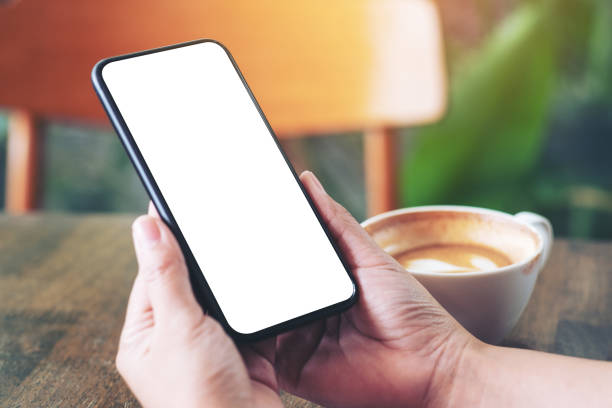 istock hands holding black mobile phone with blank screen with coffee cup on wooden table in cafe 1166566383