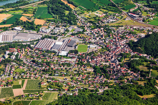Horizontal color photography of aerial top view of Culoz small French town with residential area with houses, and sports complex with football stadium in middle. Shot from Grand Colombier mountain top, from summit during a sunny summer day, in Bugey mountains, in Ain department not far from Jura and Savoie border near Culoz city, Auvergne-Rhone-Alpes region in France (Europe).
