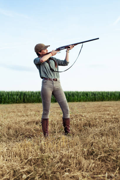 молодая женщина охотится. женщина, держащая пистолет. - rifle range стоковые фото и изображения