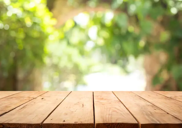 Photo of Empty wood table top on blur abstract green from garden and home area background