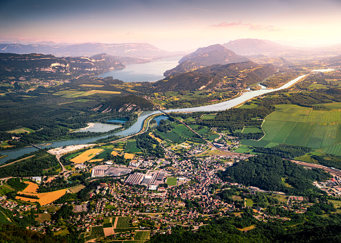 Color photography of high angle view, aerial view of beautiful French natural landscape in Bugey mountains, with small town of Culoz, the Rhone River and famous Lake Bourget in background. Shot from Grand Colombier mountain top at sunset, twilight time of the day in summer, in Bugey mountains, in Ain department not far from Jura and Savoie border near Culoz city, Auvergne-Rhone-Alpes region in France (Europe).