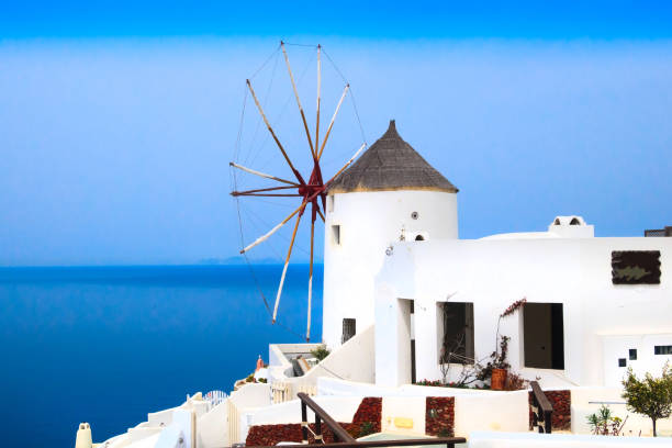 Aigiali, Greece - July 27 2024: The iconic whitewashed old windmill that stands right next to the port. Aegiali is a picturesque fishing village in Amorgos Island, Cyclades.