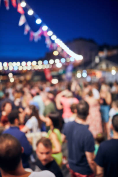 istock Blurred large group of people with de-focused lights. 1166573736