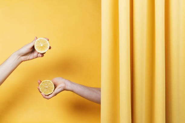istock wo women's hands holding cut lemons on yellow 1166575153
