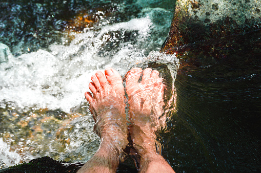 Men feets in a stream of water among the river