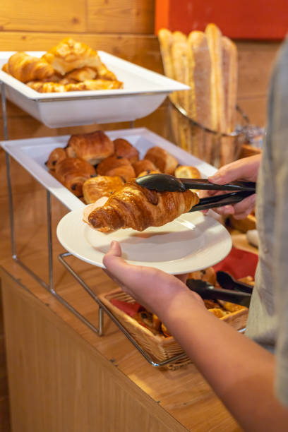 istock Human using tongs picking croissant at breakfast buffet in hotel 1166576279