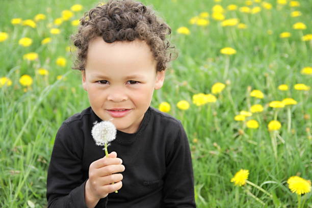istock boy smelling dandelion flowers 1166576787