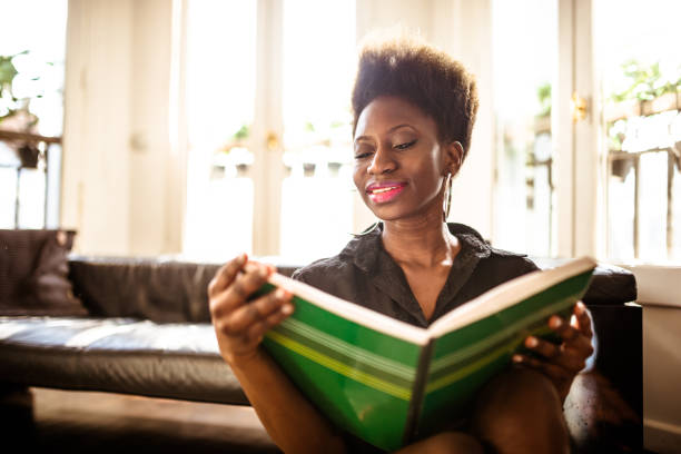 istock afro woman reading a book at home 1166578399