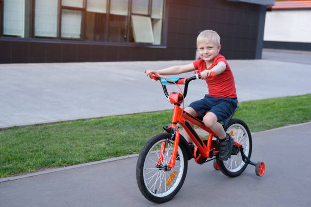 istock Handsome blond boy rides on a children's bicycle. Urban background 1166579476