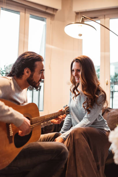 istock couple playing the guitar at home together 1166579844