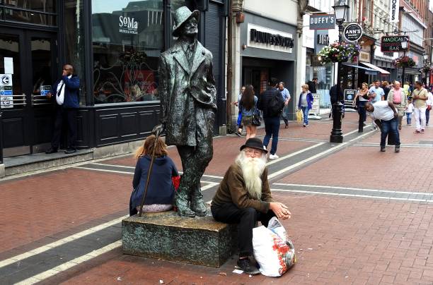 Man with long white beard 3rd August 2019, Dublin, Ireland. Man with long white beard sitting down in Earl Street Dublin city centre next to  a statue of James Joyce, sculpted by Marjorie Fitzgibbon and unveiled in 1990. bloomsday stock pictures, royalty-free photos & images