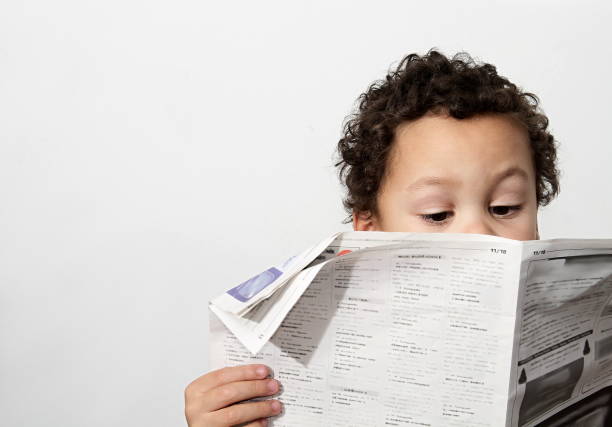 Little boy reading newspaper stock photo Little boy reading newspaper and smiling in the morning been educated with white background stock photo editorial stock pictures, royalty-free photos & images