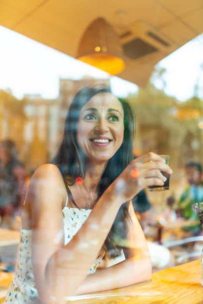 istock Beautiful woman having coffee behind a restaurant window 1166582161