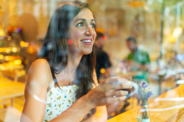 istock Beautiful woman having coffee behind a restaurant window 1166582197